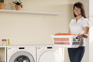 Eine Frau trägt einen Wäschekorb zur Waschmaschine